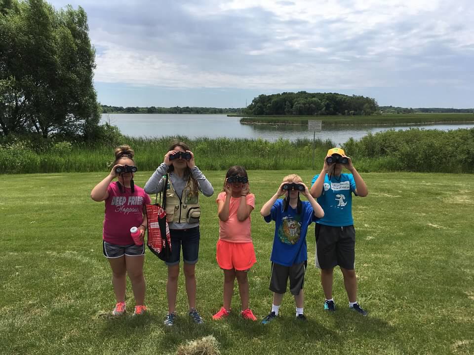 children in a field with binoculars